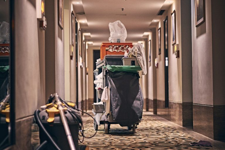 Reinigungskraft schiebt Reinigungswagen durch Flur eines Bürogebäudes bei einer intensiven Grund- und Sonderreinigung durch Glanzwerk